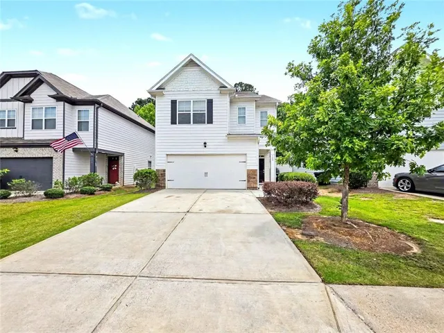 Two-story residence featuring white siding, a two-car garage, and a concrete driveway