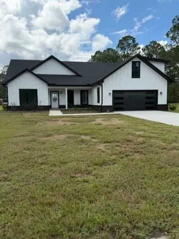 White board and batten exterior with black trim, a dark shingle roof, and a two-car garage