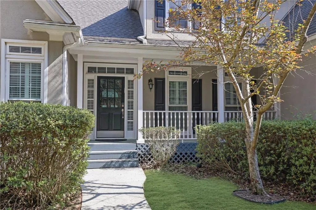 Entrance to property with roof with shingles, covered porch, and stucco siding