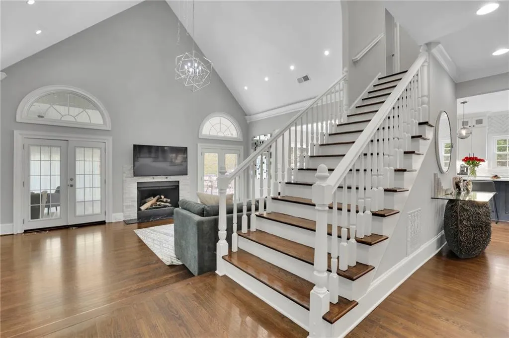 Stairway with french doors, a high ceiling, wood finished floors, a fireplace, and a chandelier