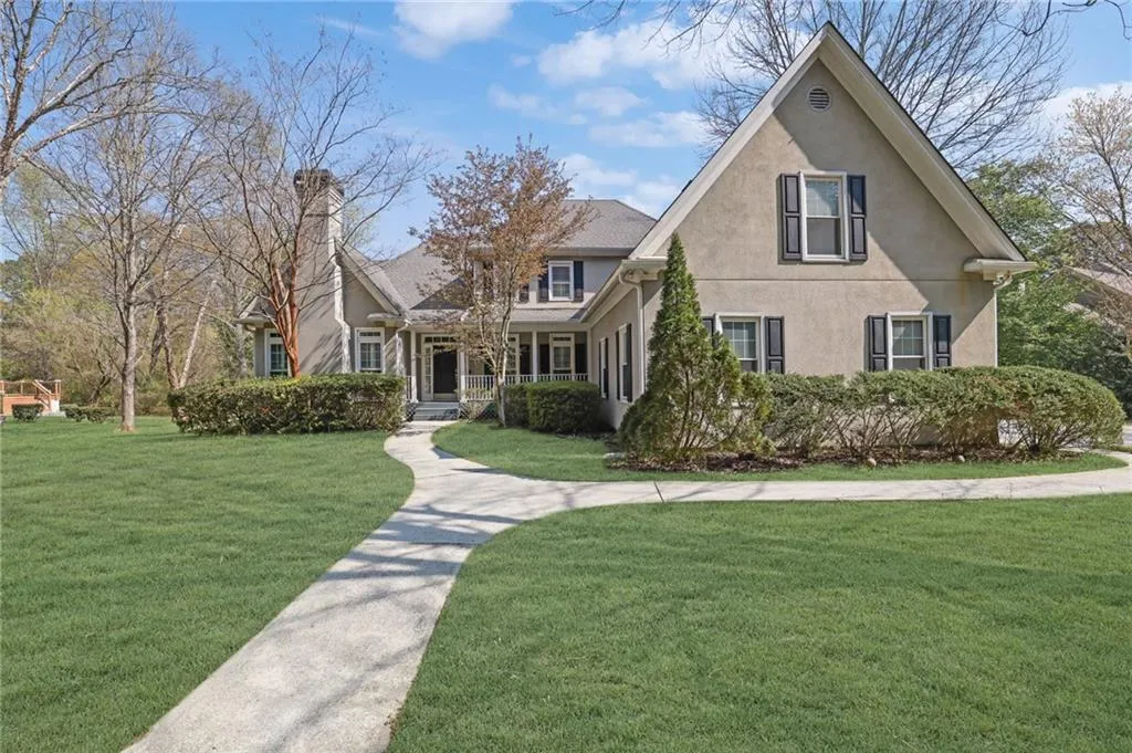 View of front of home with stucco siding, a front lawn, and a porch