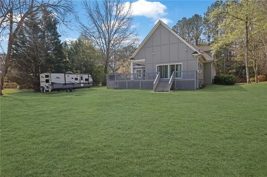 Rear view of house featuring a lawn, board and batten siding, and a deck