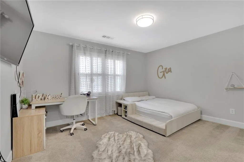 Bedroom featuring light carpet and a desk