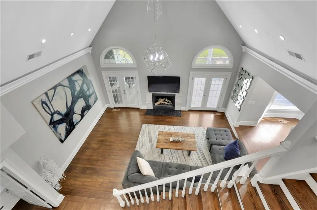 Living room featuring hanging lights, wood finished floors, french doors, a fireplace, and vaulted ceiling