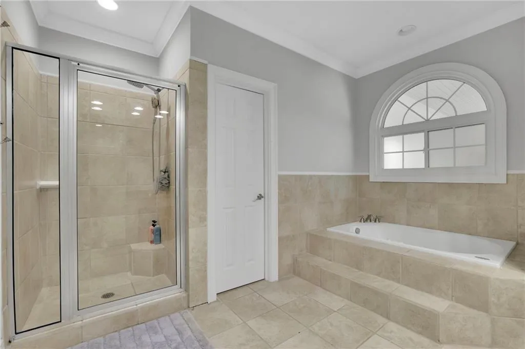 Full bathroom featuring crown molding, a bath, a shower stall, and light tile patterned floors