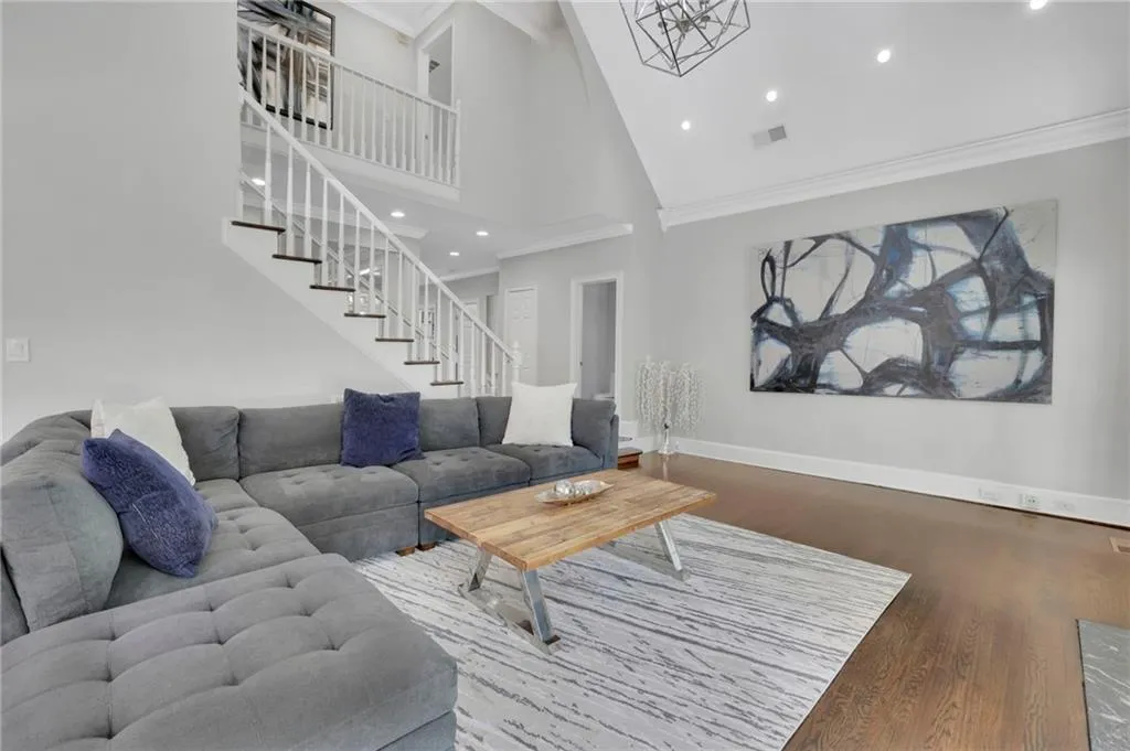 Living room featuring wood finished floors, crown molding, lofted ceiling, and recessed lighting