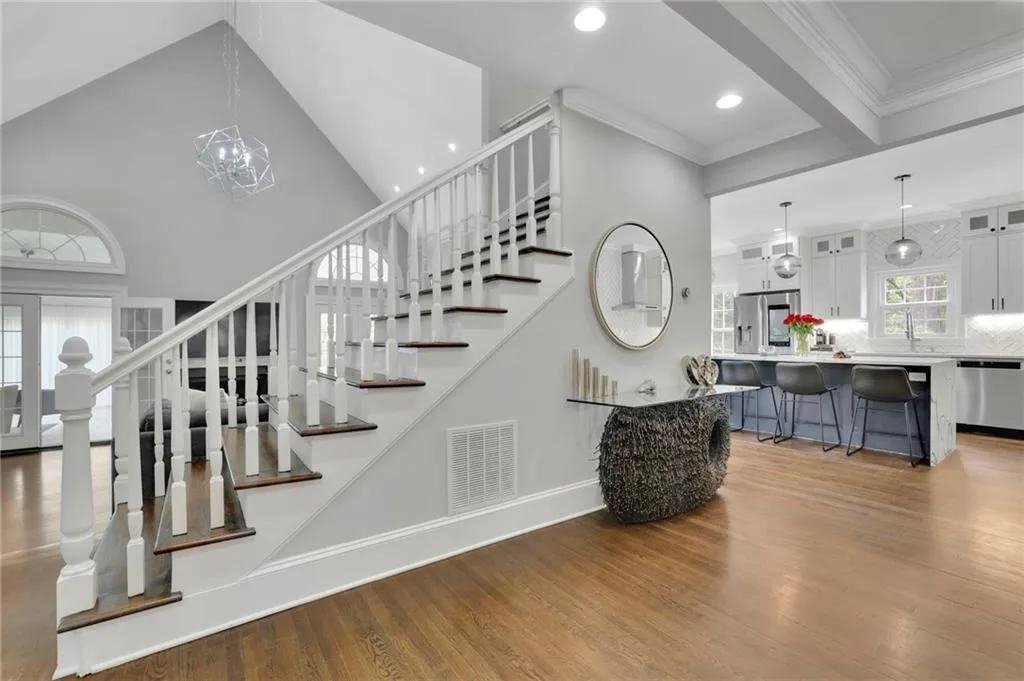 Stairway with crown molding, wood finished floors, and suspended lighting