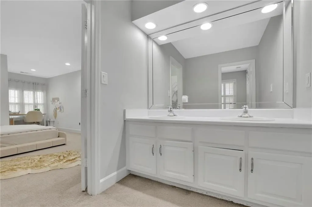Ensuite bathroom with light carpet, double vanity, and recessed lighting