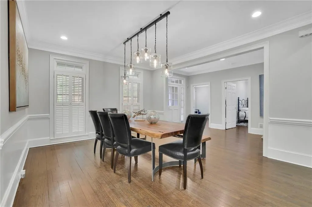 Dining area with dark wood-style flooring, wainscoting, crown molding, a decorative wall, and recessed lighting