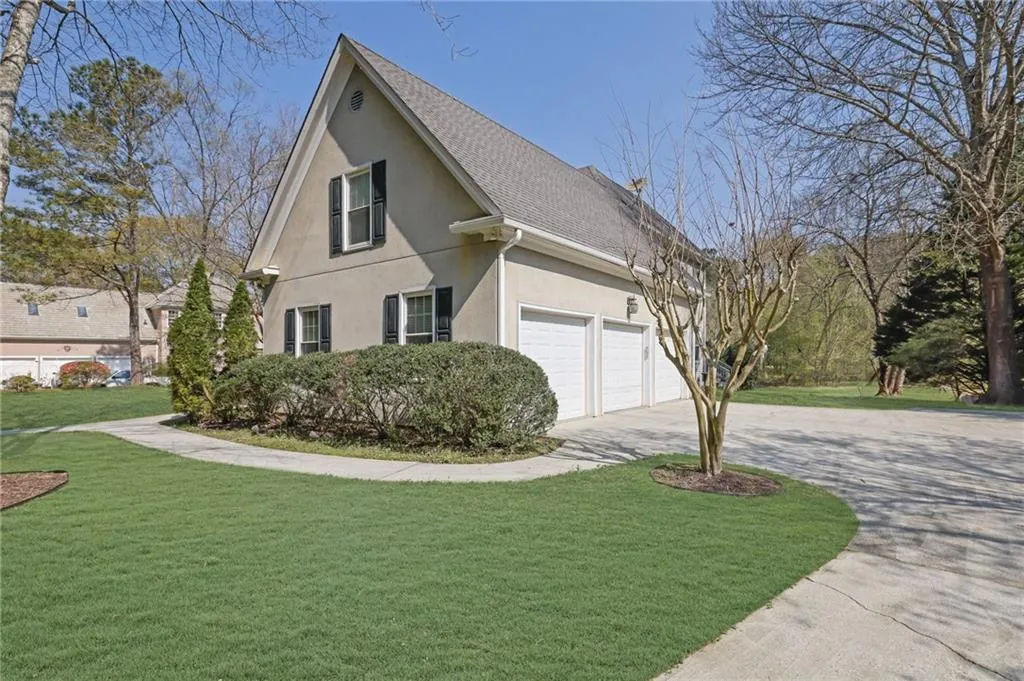 View of home's exterior with stucco siding, a lawn, driveway, roof with shingles, and a garage