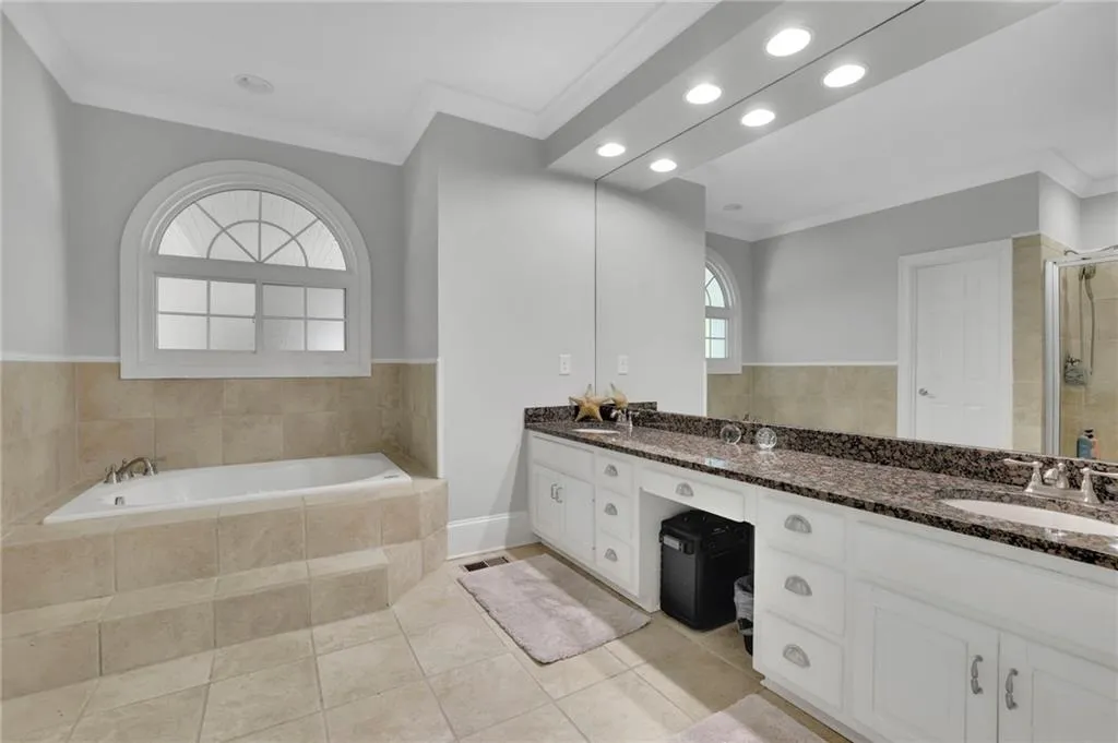 Full bathroom featuring crown molding, double vanity, a bath, recessed lighting, and light tile patterned floors