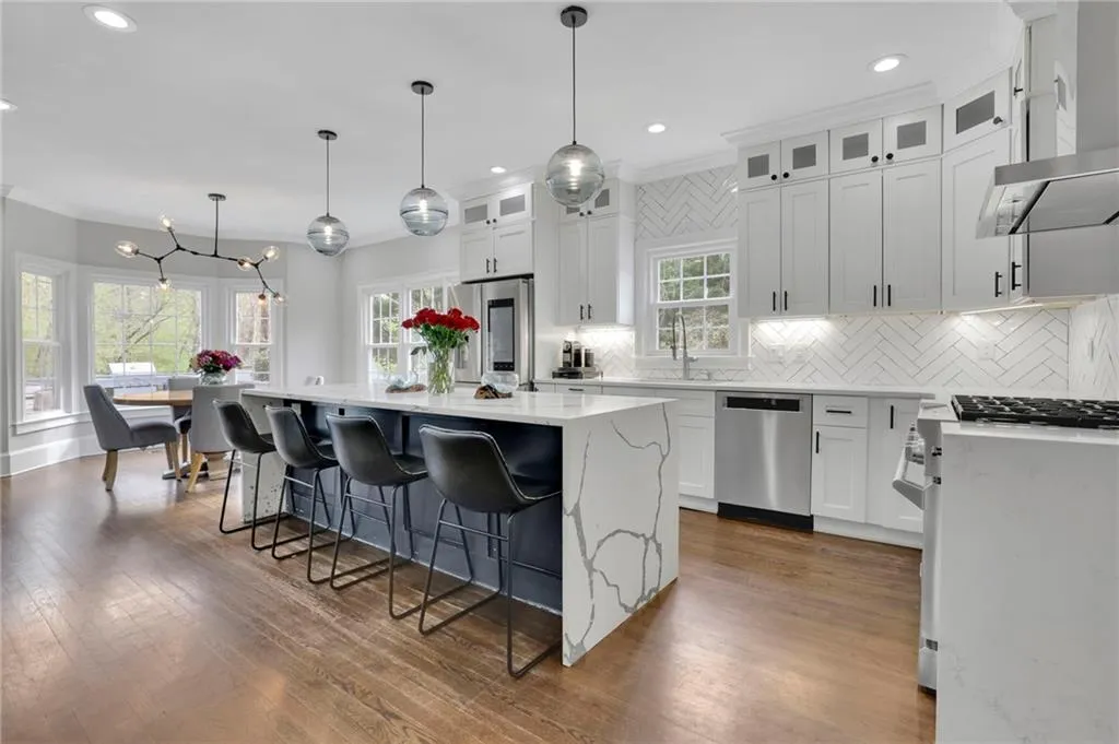 Kitchen featuring light stone countertops, crown molding, white cabinets, stainless steel appliances, and decorative backsplash