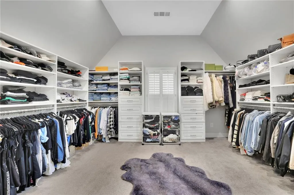 Walk in closet featuring light colored carpet and vaulted ceiling