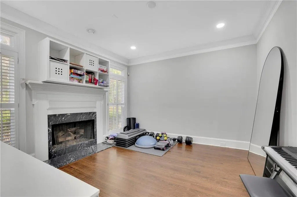 Living area with ornamental molding, wood finished floors, a high end fireplace, and recessed lighting