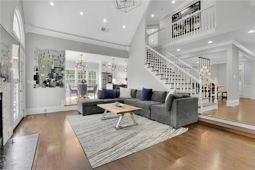Living room with suspended lighting, crown molding, a fireplace, wood finished floors, and a high ceiling