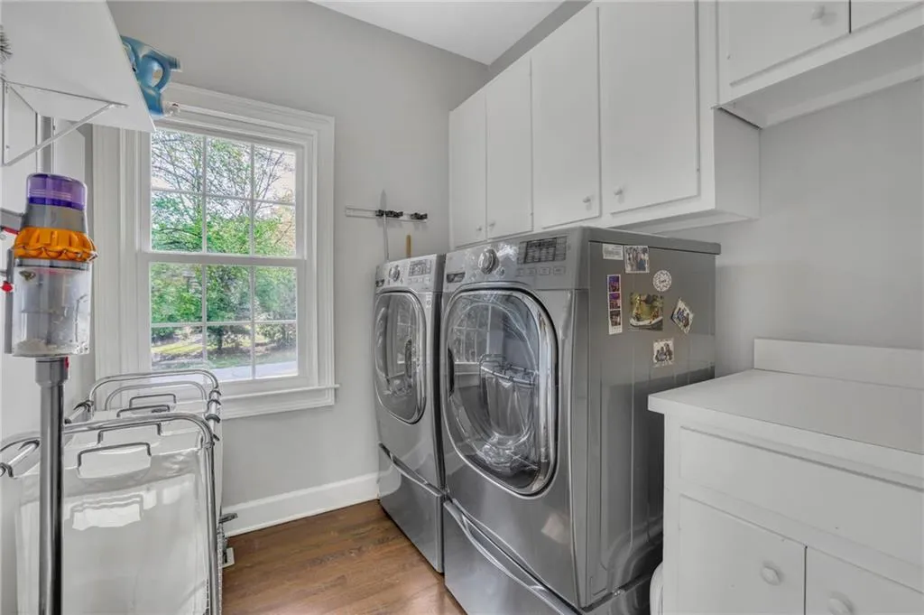 Laundry area featuring dark wood-style floors, washing machine and clothes dryer, and cabinet space