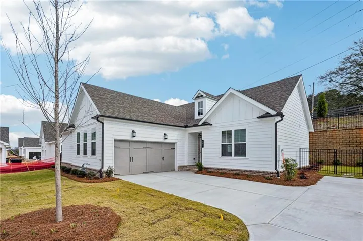 White plank siding exterior with a dark shingle roof, featuring a two-car garage with light gray doors and black hardware