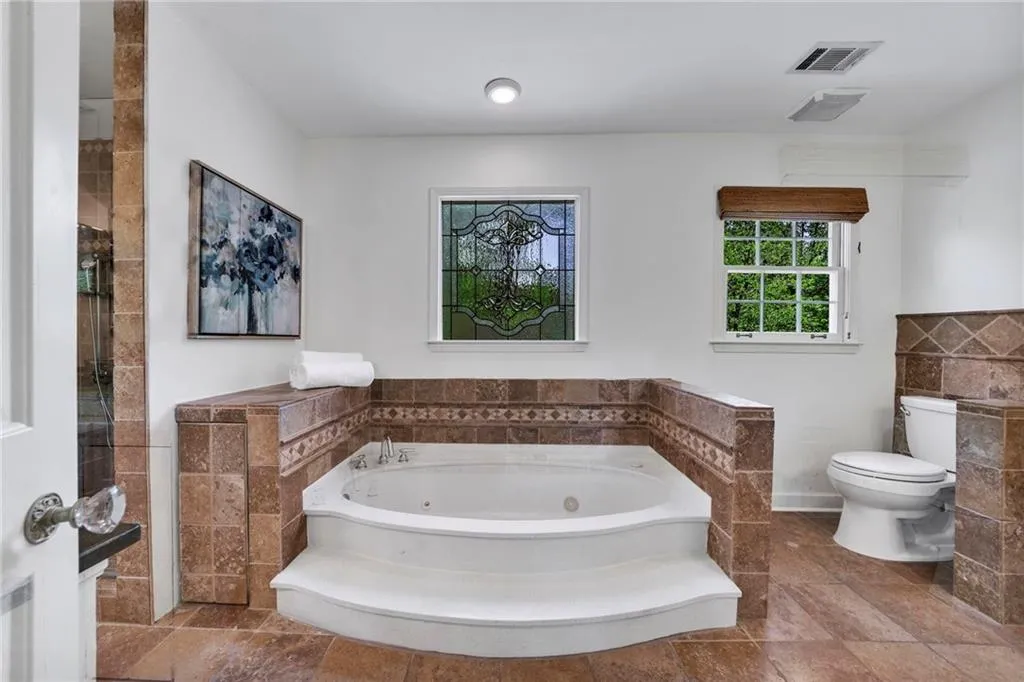 Bathroom featuring tile floors, separate shower and tub, and toilet Bathroom featuring tile floors, separate shower and tub, and toilet