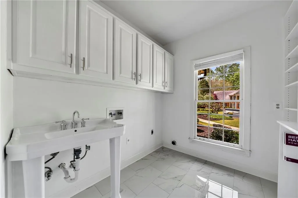Laundry room featuring electric dryer hookup, cabinets, light tile floors, and hookup for a washing machine Laundry room featuring electric dryer hookup, cabinets, light tile floors, and hookup for a washing machine