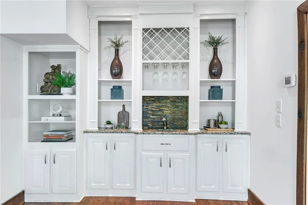 Bar with sink, white cabinets, stone countertops, and light wood-type flooring Bar with sink, white cabinets, stone countertops, and light wood-type flooring
