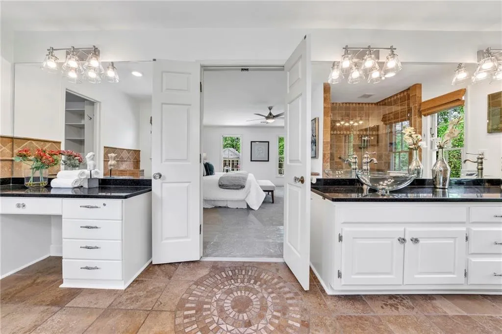 Master bath featuring tile flooring, his/her vanities, garden tub, large walk-in shower, granite countertops, and large closet with built-ins Master bath featuring tile flooring, his/her vanities, garden tub, large walk-in shower, granite countertops, and large closet with built-ins