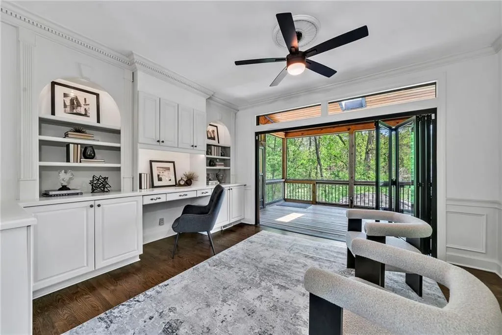 Office area featuring ceiling fan, built in shelves, hardwood flooring, crown molding, and built in desk Office area featuring ceiling fan, built in shelves, hardwood flooring, crown molding, and built in desk