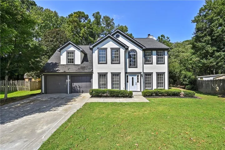 Two-story residence with a two-car garage, white facade, and dark trim accents