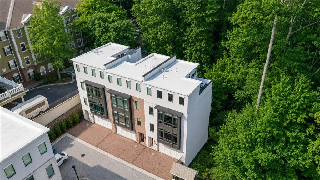 Contemporary townhouse featuring a multi-level design, flat roofline, and varied exterior materials including white siding and brick accents