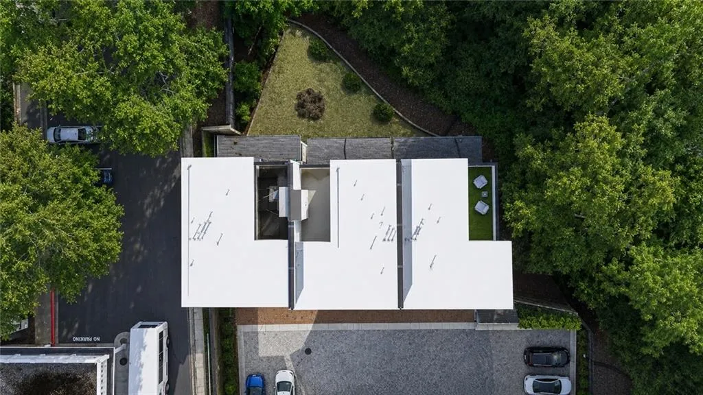 Modern building featuring a flat roofline, integrated green space, and a paver stone courtyard