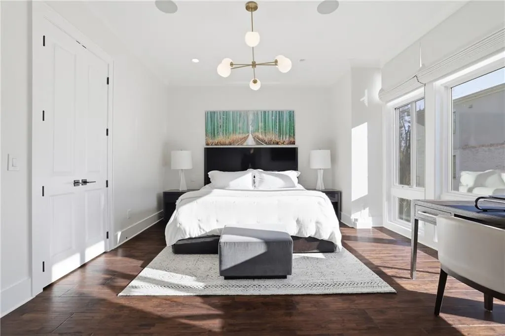 Spacious room featuring rich wood-finish flooring, bright white walls, and a contemporary multi-globe chandelier