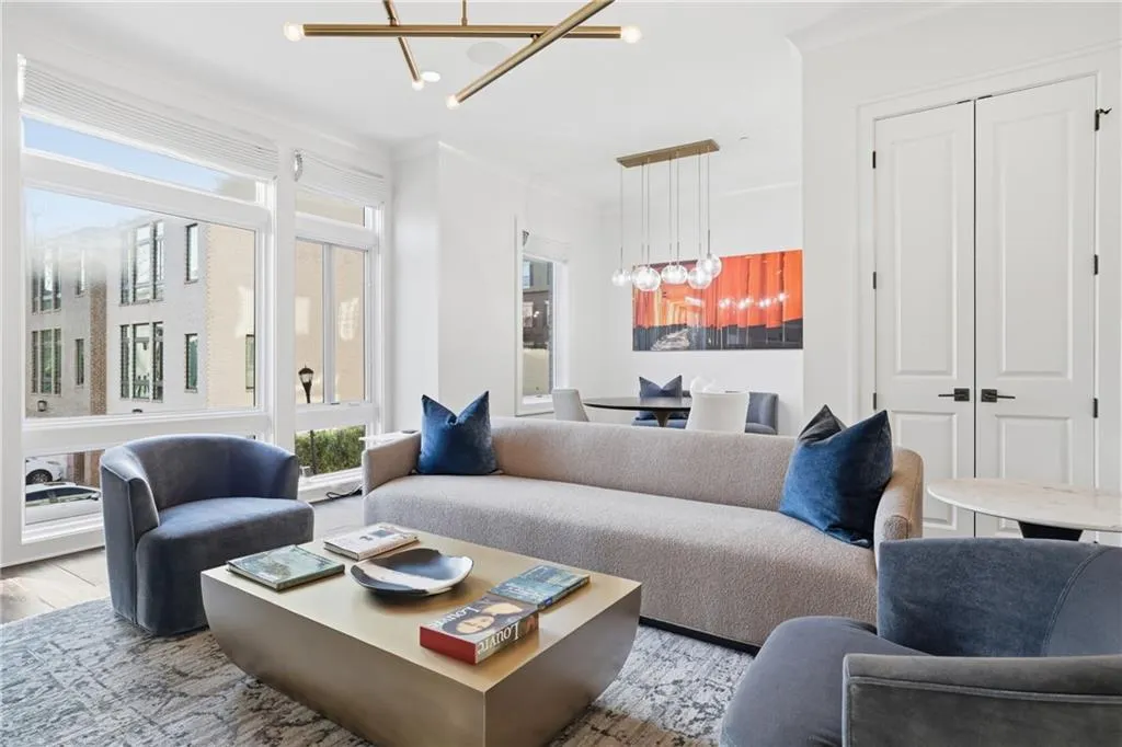 Open-concept living space with expansive windows, wood-finish flooring, and a contemporary linear chandelier