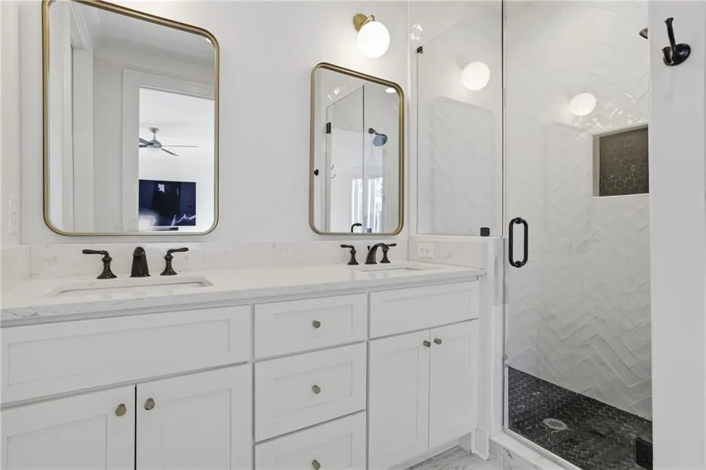 Dual vanity with white cabinetry, matte black hardware, and rectangular gold-framed mirrors
