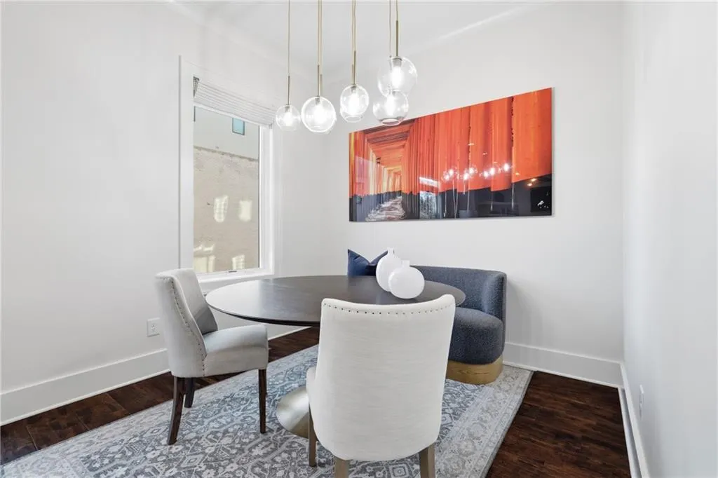 Dining area featuring contemporary pendant lighting, dark wood-finish flooring, crisp white baseboards, and a single window with blinds