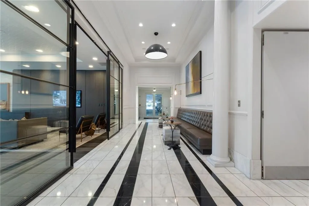 Hall featuring recessed lighting, crown molding, inlaid floor details, marble finish flooring, and a raised ceiling