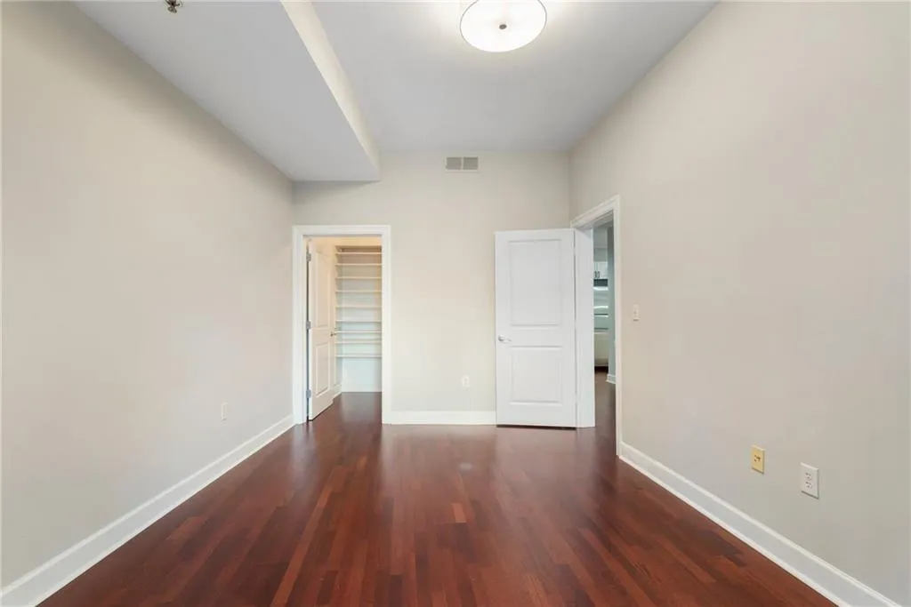 Unfurnished bedroom with wood finished floors, baseboards, and a spacious closet