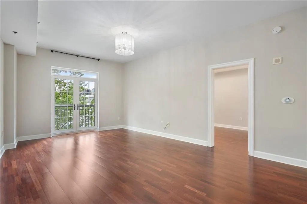Empty room featuring a chandelier, dark wood-style flooring, and baseboards