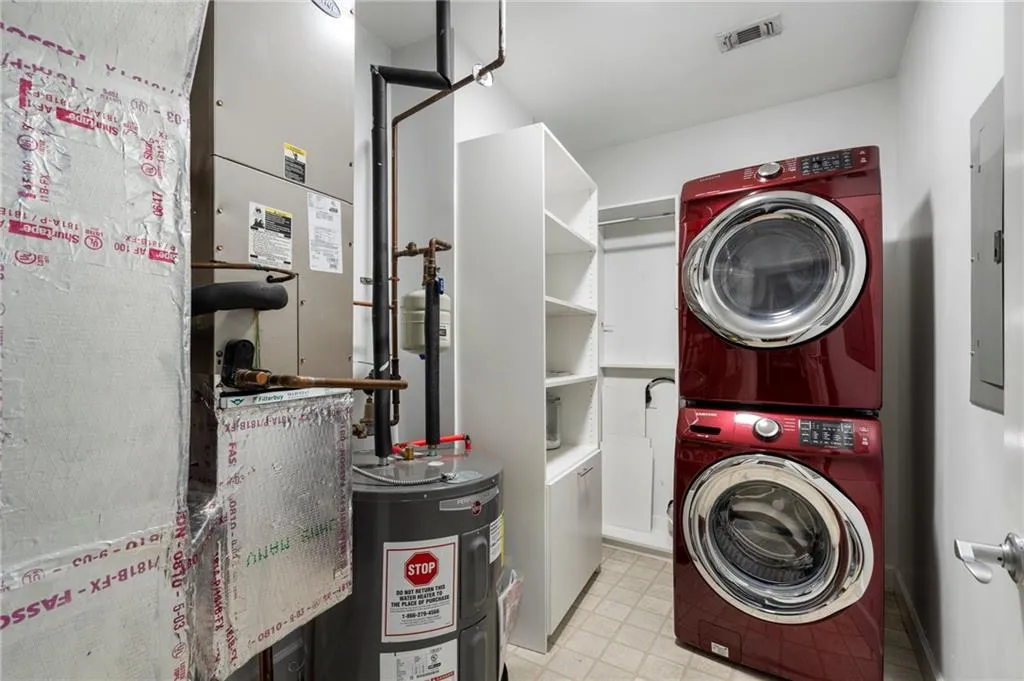 Laundry area with stacked washer / drying machine, electric water heater, heating unit, and electric panel