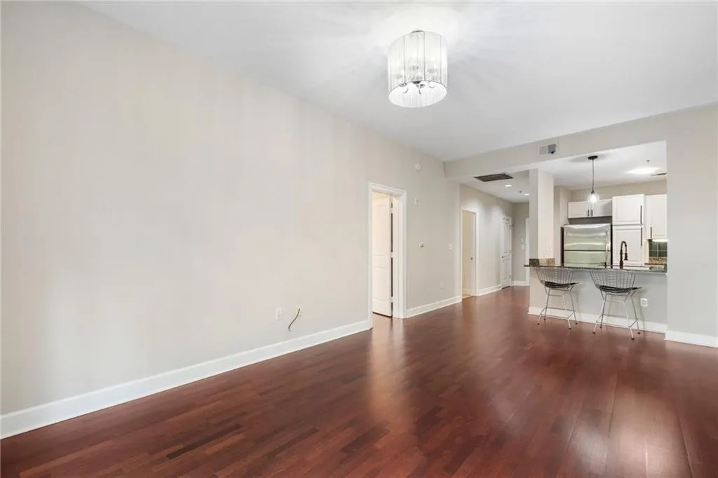 Unfurnished living room featuring dark wood-style floors, a chandelier, baseboards, and a sink