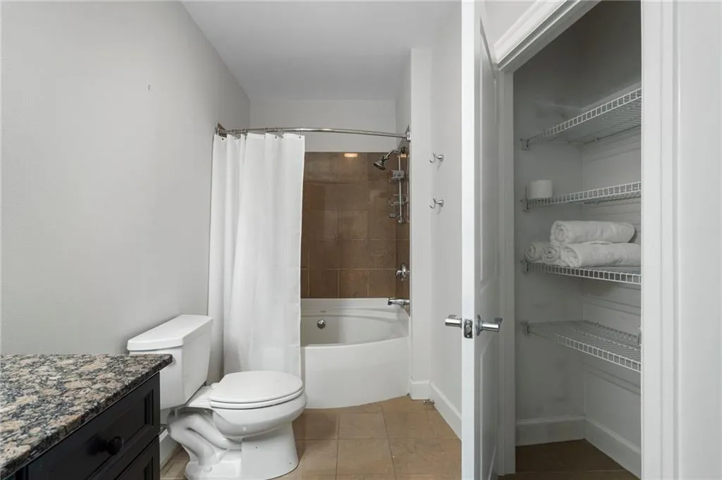 Bathroom featuring tile patterned floors, shower / bath combo with shower curtain, vanity, toilet, and baseboards