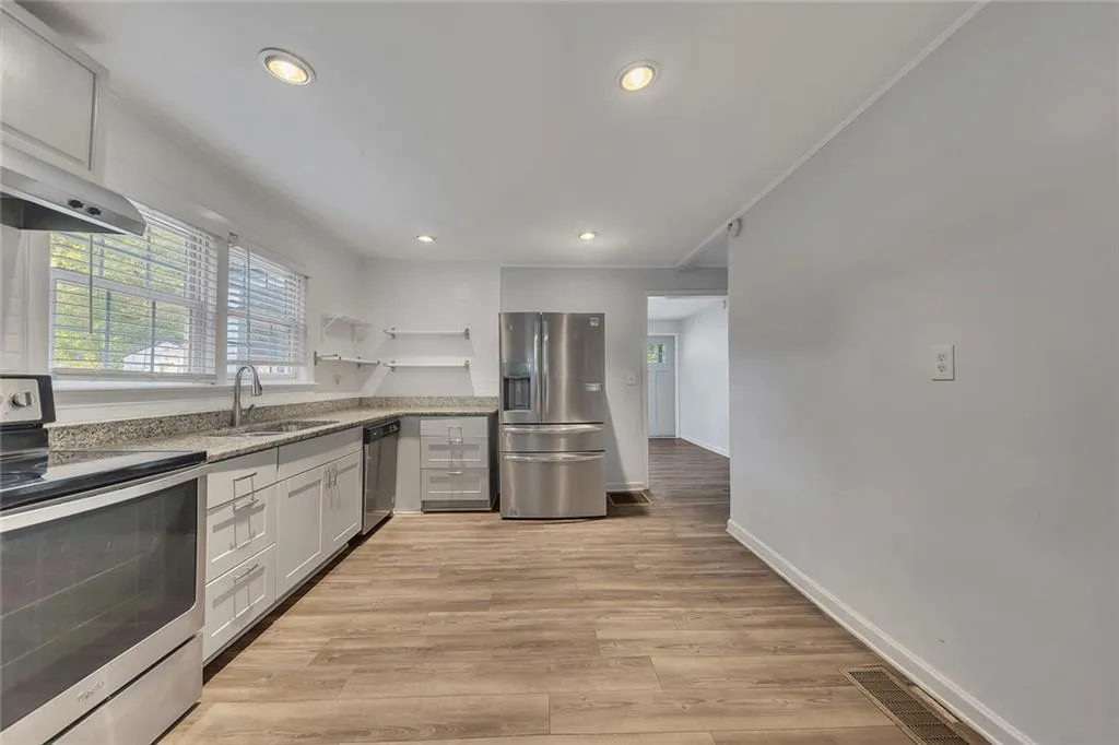 Kitchen featuring stainless steel appliances, a sink, light stone counters, recessed lighting, and baseboards