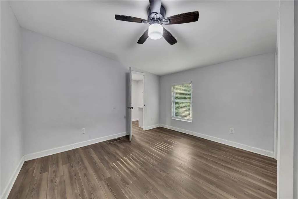 Unfurnished room with wood finished floors, baseboards, and ceiling fan