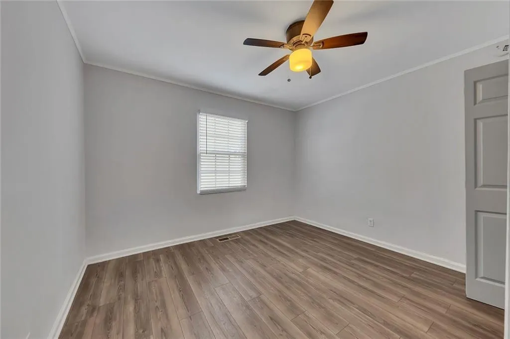 Unfurnished room featuring ornamental molding, wood finished floors, baseboards, and a ceiling fan
