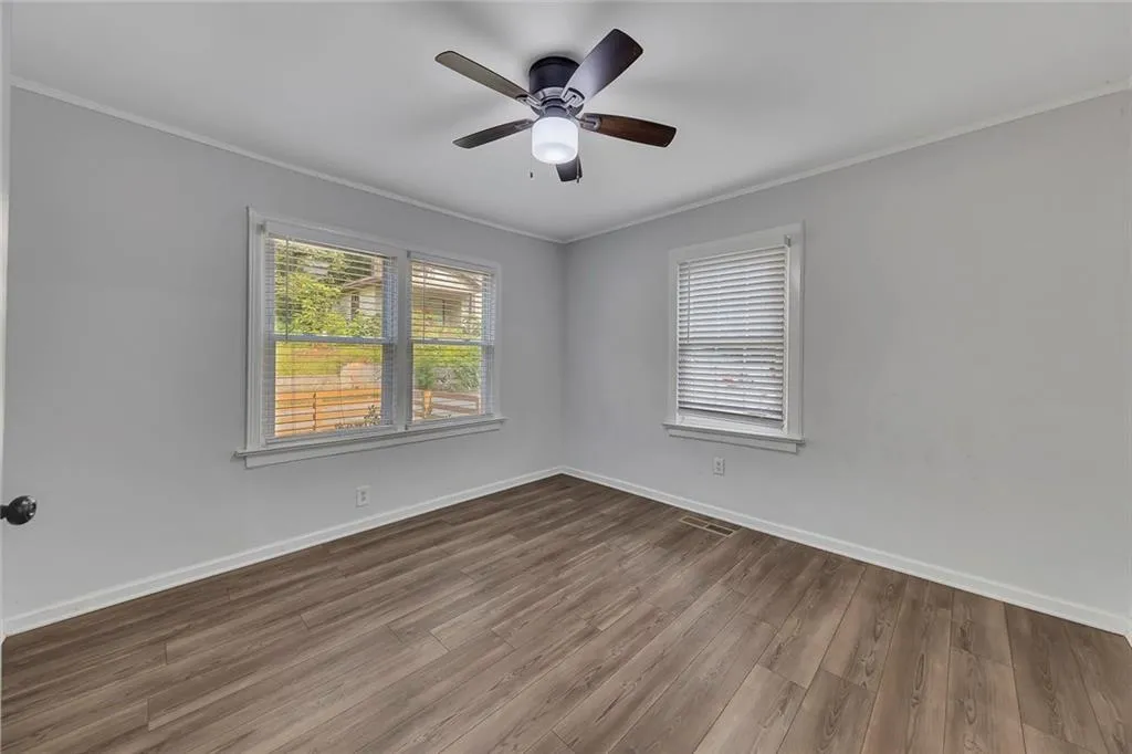 Unfurnished room featuring crown molding, wood finished floors, baseboards, and a ceiling fan