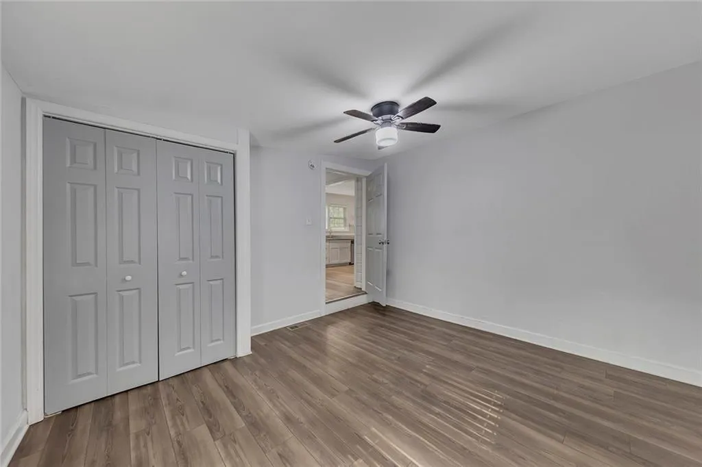 Unfurnished bedroom featuring wood finished floors, baseboards, a closet, and a ceiling fan