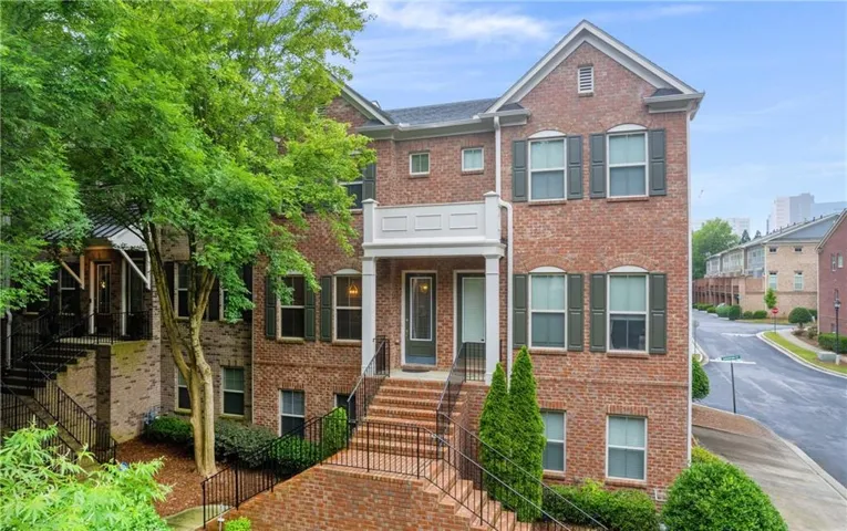 Multi-level brick exterior with dark shutters, white columns, and a second-story balcony