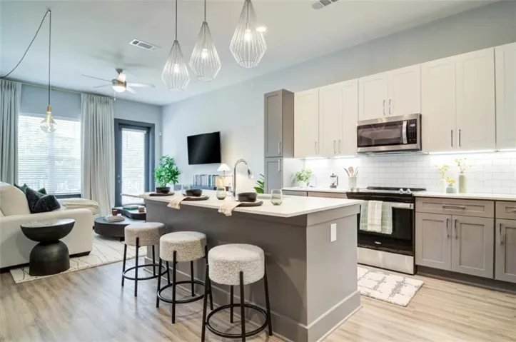 Kitchen with open floor plan, appliances with stainless steel finishes, decorative light fixtures, a kitchen breakfast bar, and an island with sink