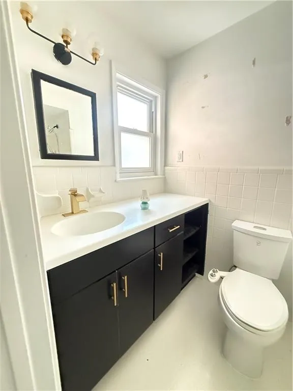 Bathroom vanity featuring a white countertop with an integrated sink, black cabinetry with gold-toned hardware, and a gold-toned faucet