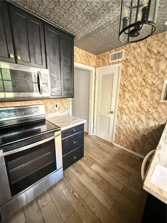 Kitchen featuring dark cabinetry, stainless steel appliances, and light-toned countertops