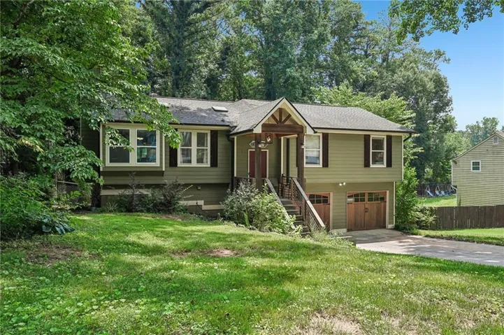 Split-level residence featuring a prominent front entrance with an extended porch roof, two wood-finish garage doors, and a bay window