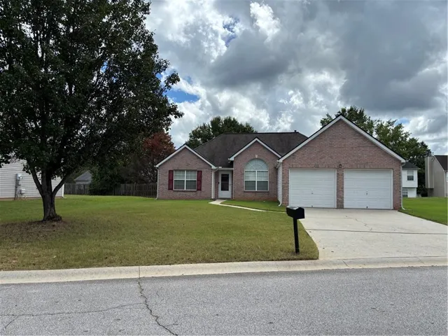 Brick exterior residence featuring a two-car garage, established front yard, and a paved driveway